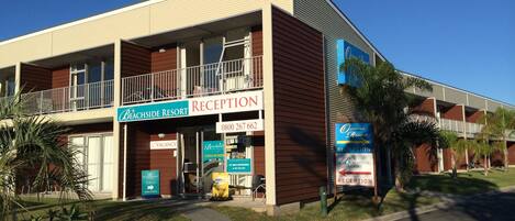 Un edificio a due piani con un'area reception, un cartello con scritto 'Beachside Resort' e un segnale con la scritta 'Host'.