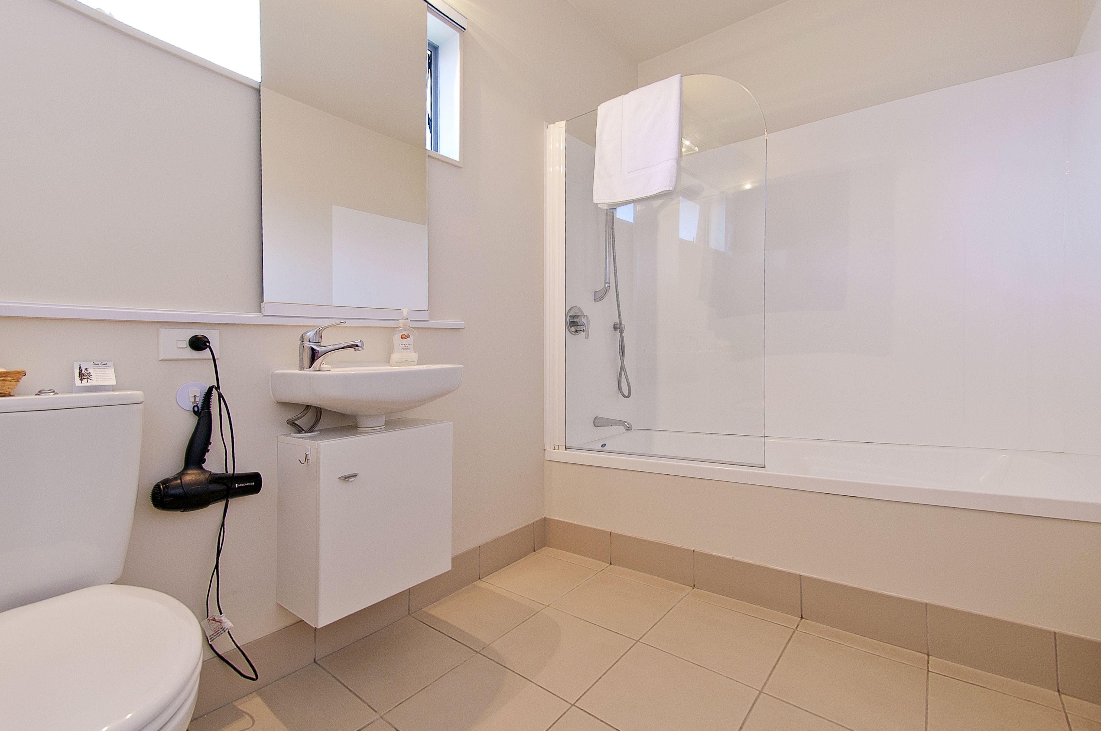 Une salle de bain moderne équipée de toilettes, d’un lavabo et d’une douche à parois de verre.