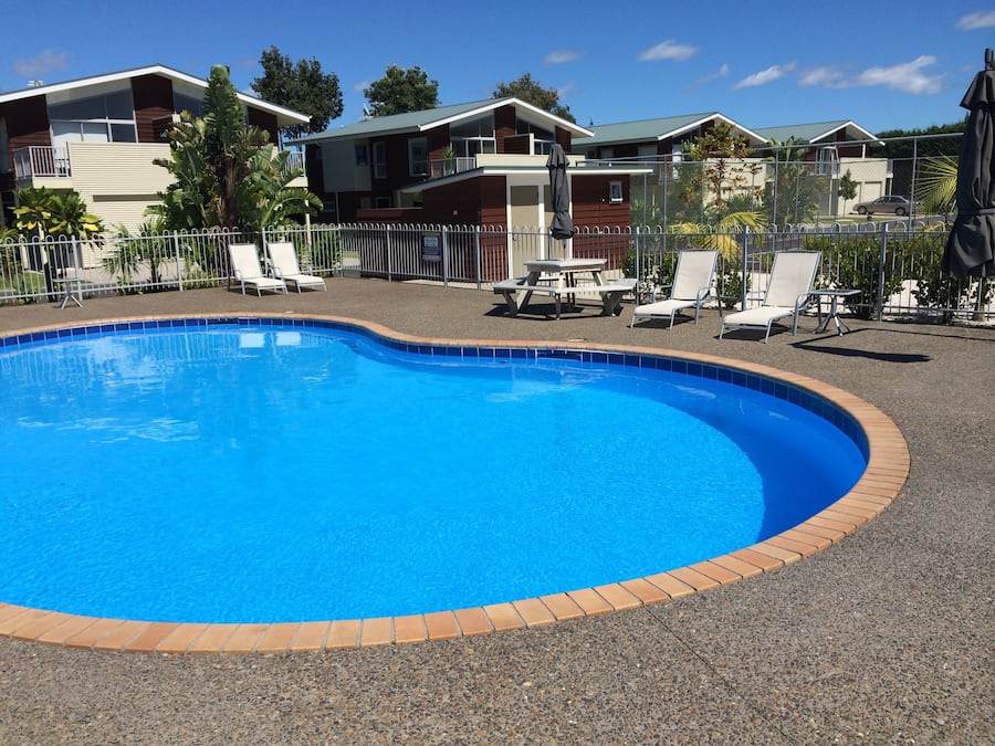 Una piscina al aire libre, sombrillas, sillones reclinables de piscina