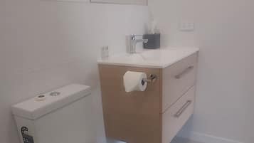 Een moderne badkamer met toilet, wastafel en spiegel.
