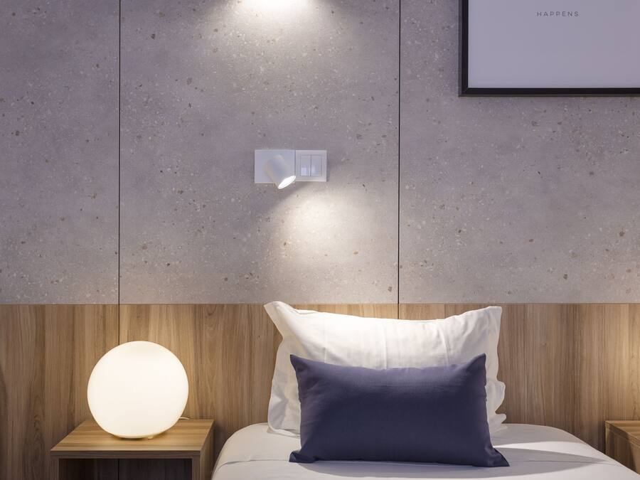 Une chambre moderne avec une tête de lit en bois, une lampe de chevet ronde, un tableau encadré au mur et une table de chevet.