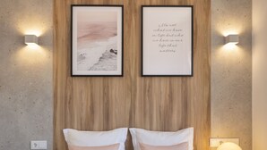 Une chambre à coucher avec un lit, deux lampes fixées au mur et deux tableaux encadrés accrochés au mur.