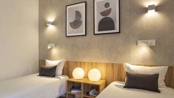 A modern hotel room with two beds, a wooden nightstand, and abstract artwork on the wall.