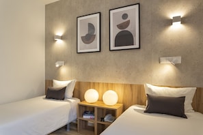 A modern hotel room with two beds, a wooden nightstand, and abstract artwork on the wall.
