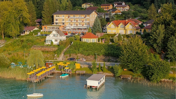 A lakeside hotel with multiple buildings, a dock with boats, and a well-maintained garden area.