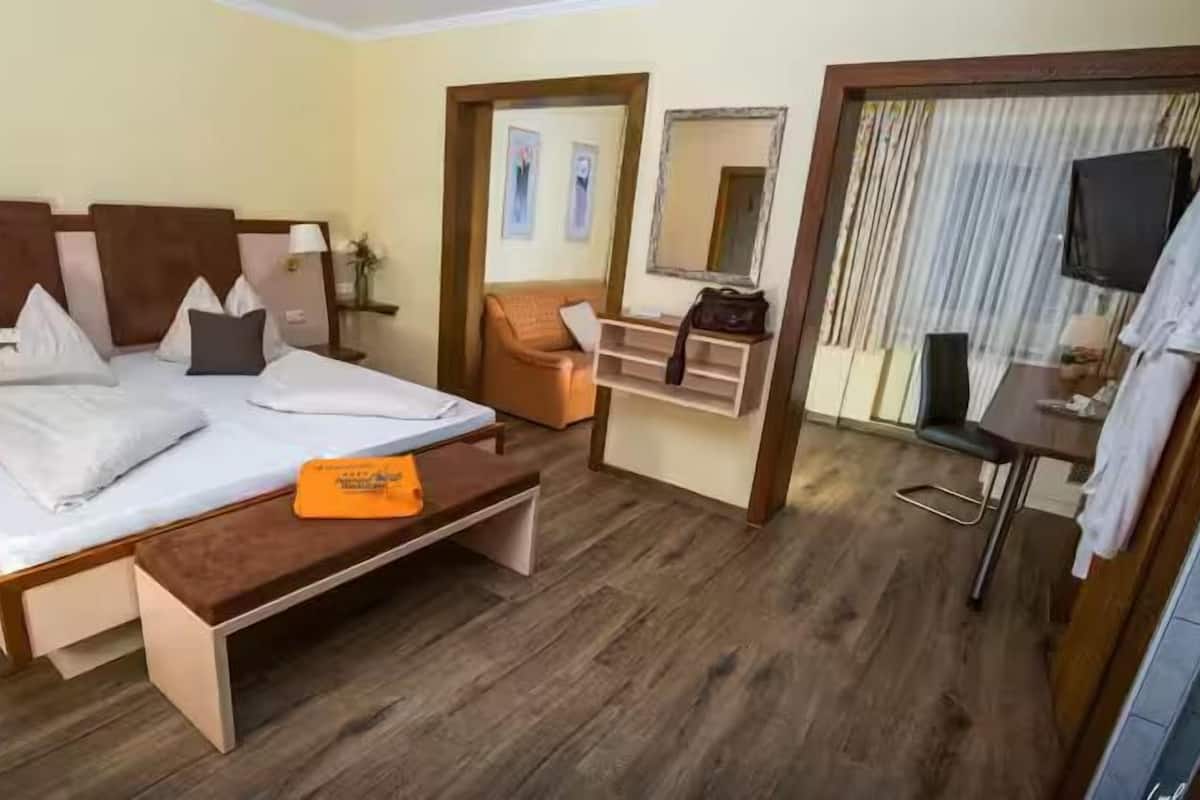 Hotelkamer met een bed, bureau, stoel, televisie en een spiegel in de badkamer.