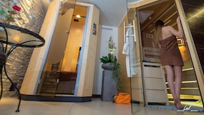 A sauna room with a glass door, a wooden bench, and a towel rack.
