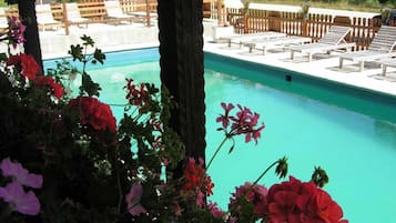 Una piscina al aire libre de temporada, sillones reclinables de piscina