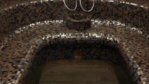 Una bañera de hidromasaje circular con paredes de mosaicos y tres grifos.