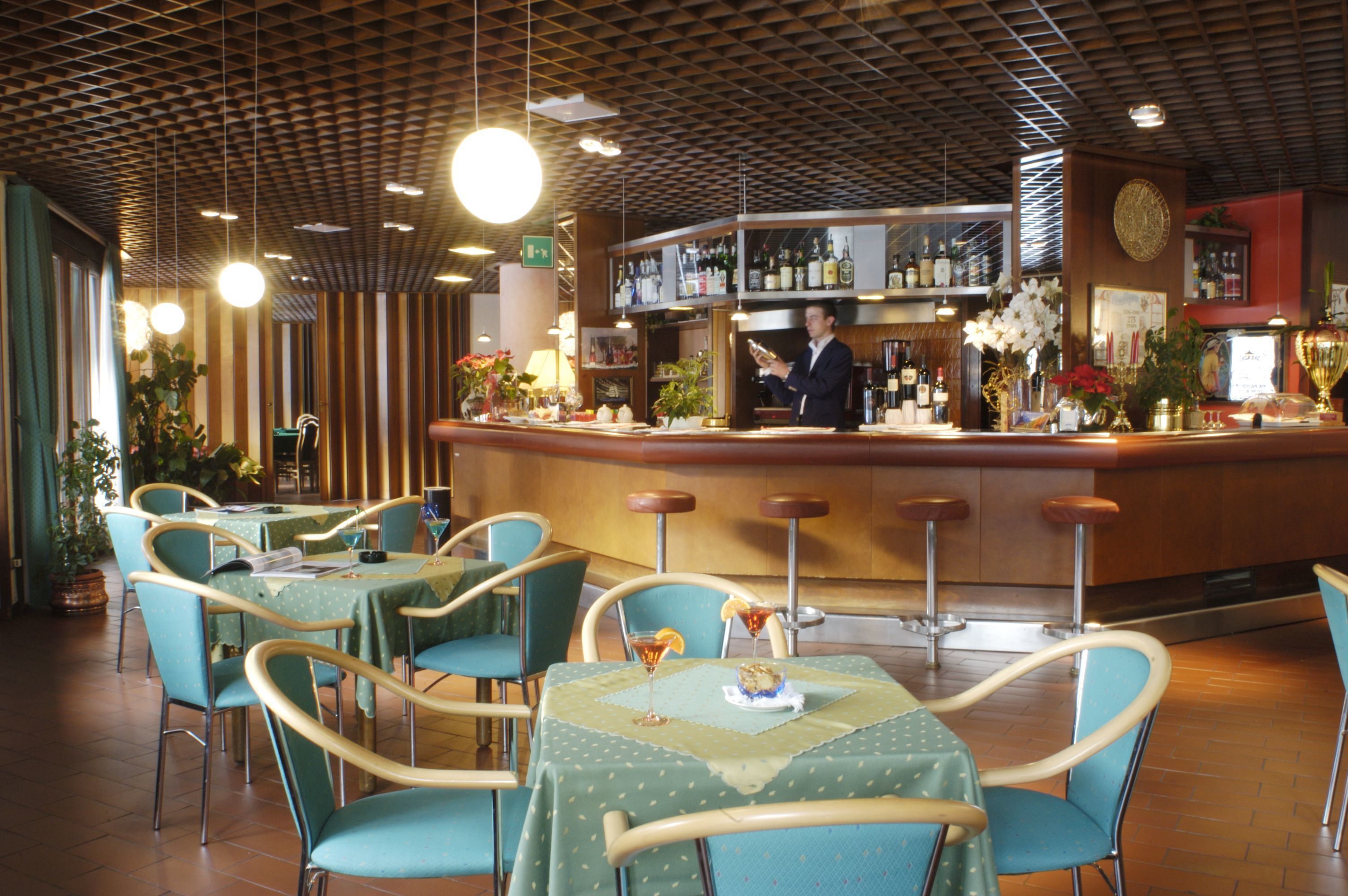 Ein Restaurant mit Barbereich, Tischen und Stühlen sowie verschiedenen Pflanzen und Blumen.