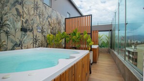 A modern outdoor hot tub area with a wooden deck, tropical wallpaper, and a view of the city. - Hotel Soratama (Pereira)