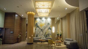 A modern lobby with a large wall mural, a chandelier, and a seating area with a sofa and armchairs. - Hotel Soratama (Pereira)