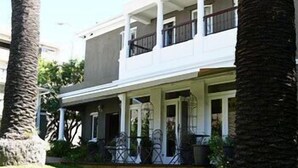 A two-story house with a covered porch, palm trees, and a well-maintained lawn. - Albatross Guest House (Cape Town)