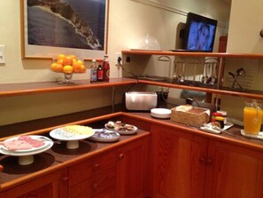 A kitchen with a fruit bowl, a toaster, and various breakfast items. - Albatross Guest House (Cape Town)
