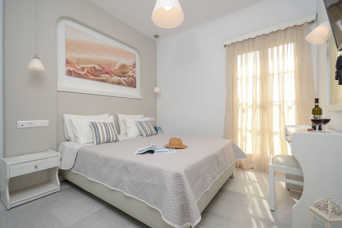 A neatly arranged bedroom with a bed, bedside tables, a reading lamp, and a window with curtains.