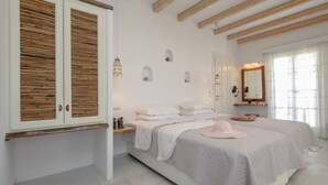 Un dormitorio con una cama grande, vigas de madera, un armario y un espejo.