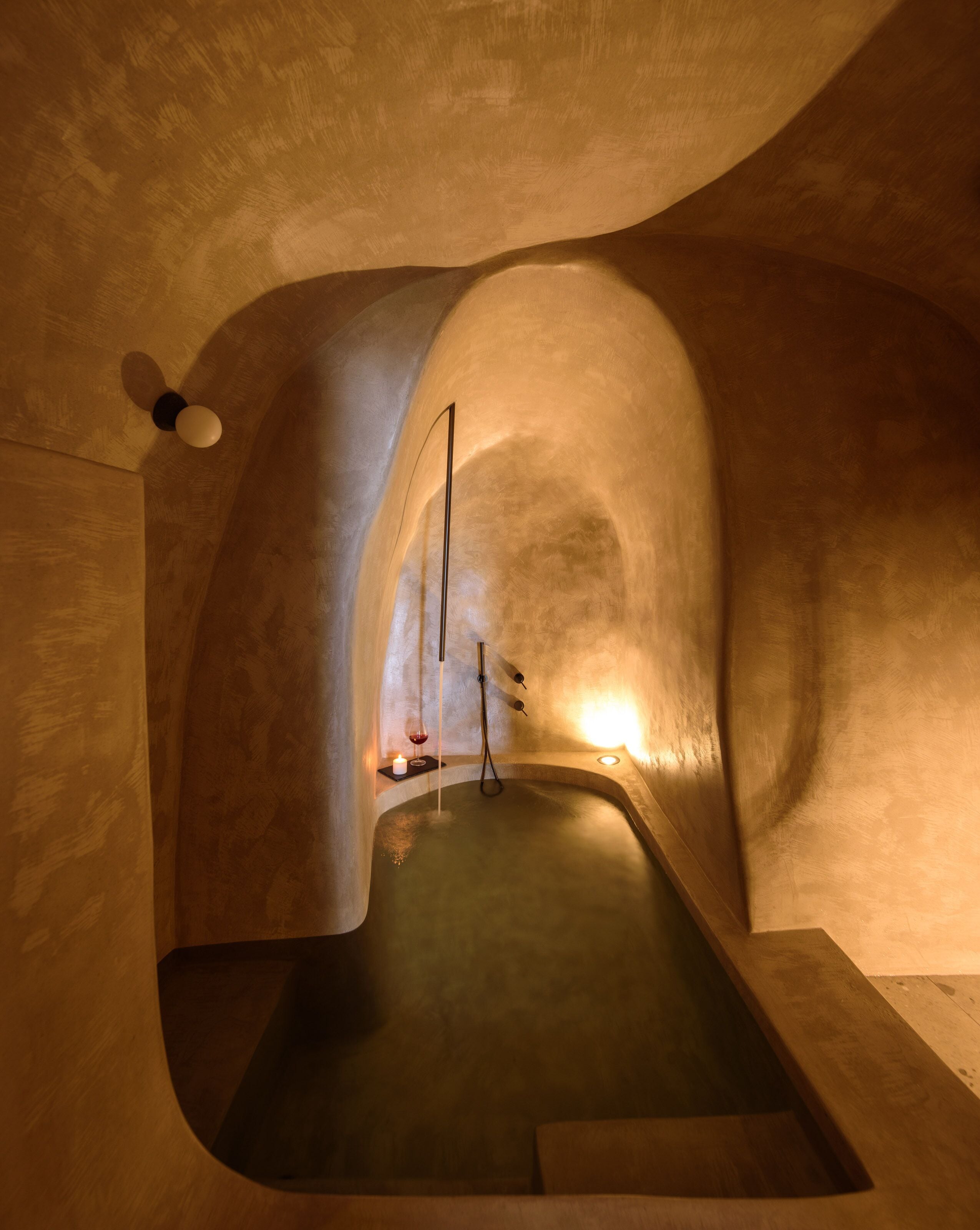 Um quarto de spa com uma banheira grande, um ventilador de teto e uma vela sobre uma mesinha lateral.