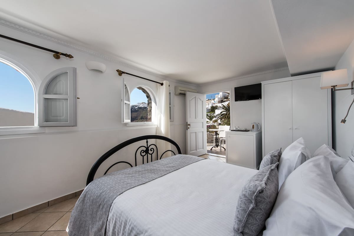 A bedroom with a bed, a window, and a view of the outside.