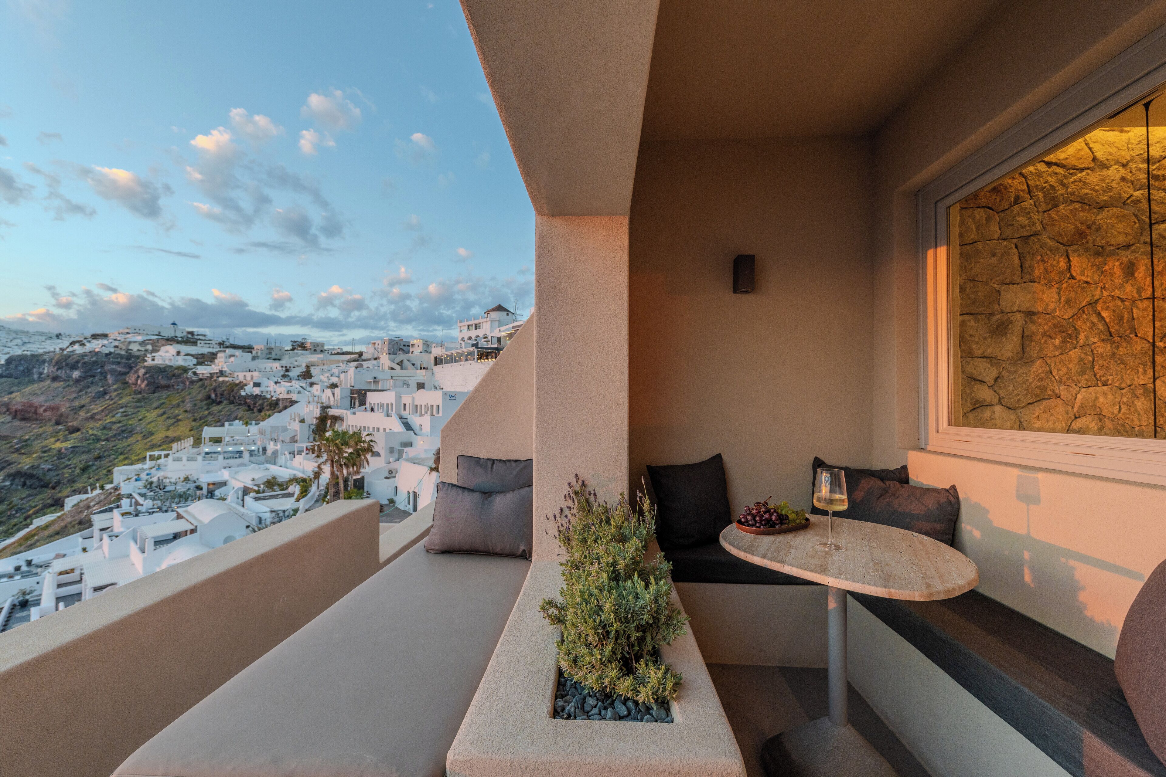 Un balcon avec un espace salon, une petite table et une vue sur une ville côtière.