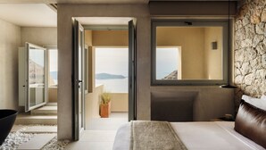 Un dormitorio moderno con una cama grande, una pared de piedra y vistas al mar.