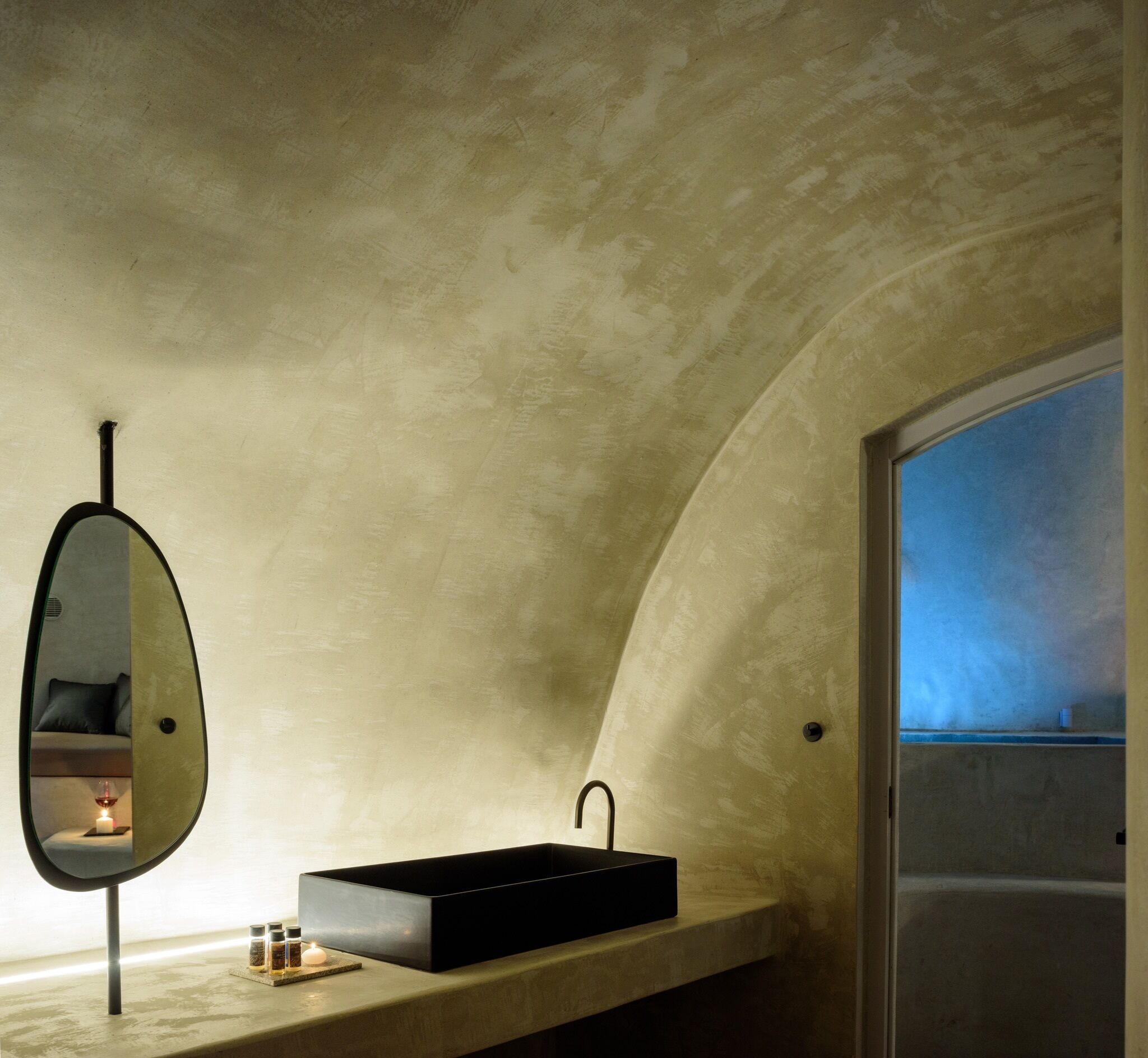 Une salle de bain avec un plafond incurvé, un lavabo rectangulaire, un miroir et une fenêtre.