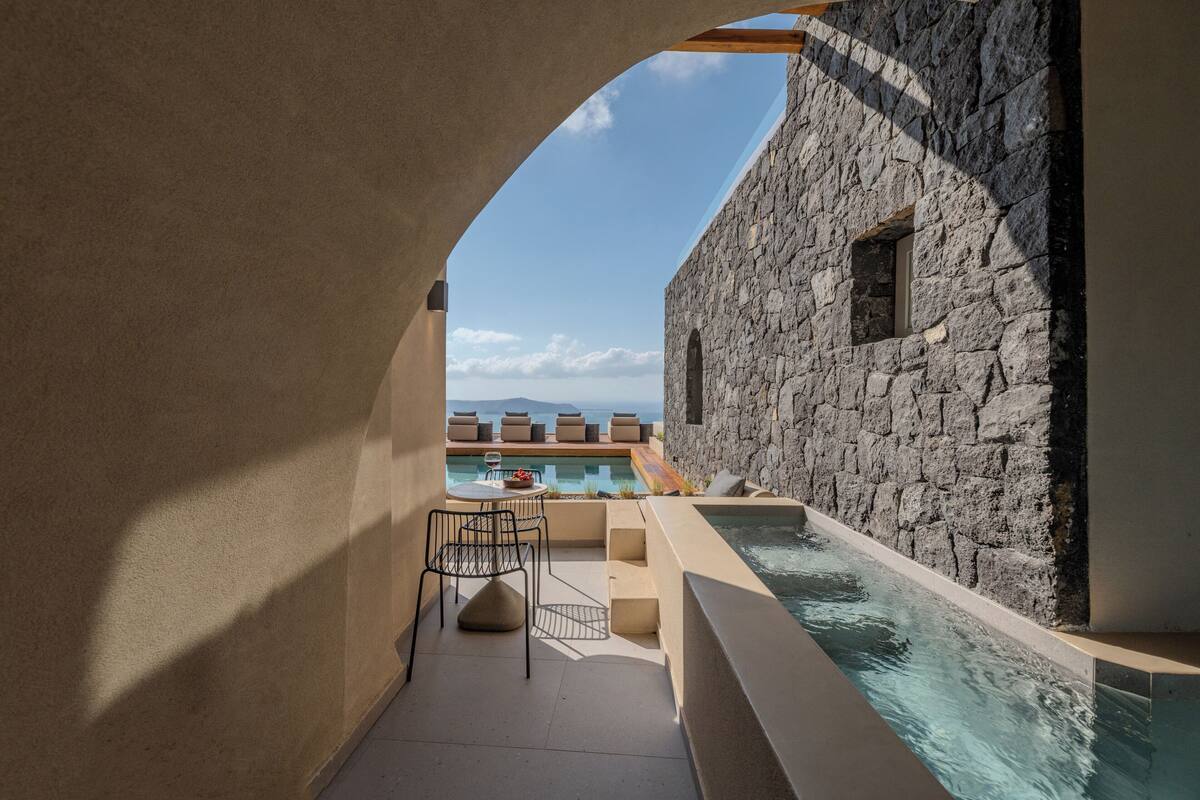 A stone building with a pool, a chair, and a table.