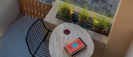 A balcony with a round table, two chairs, a potted plant, and a book.