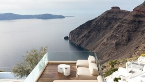 Una terraza con vistas al mar y a los acantilados, que cuenta con una zona de estar con mesa y sillas.