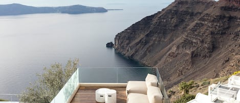 A terrace with a view of the sea and cliffs, featuring a seating area with a table and chairs.