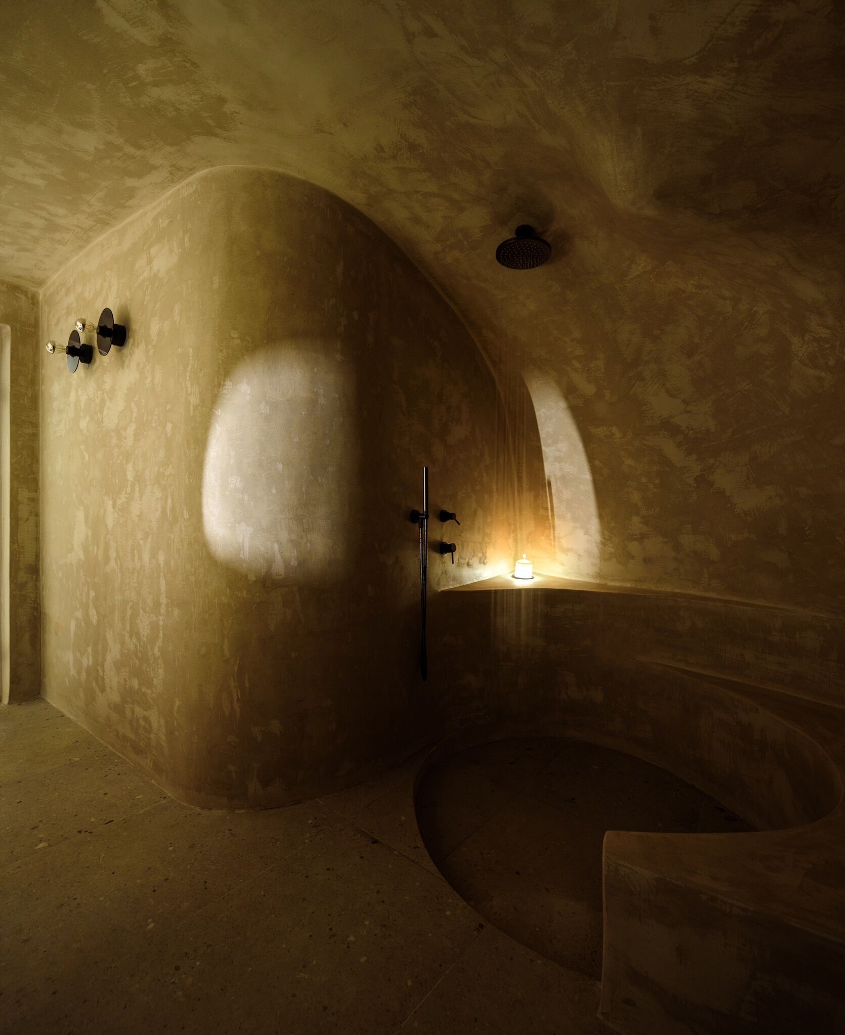 A spacious, dimly lit room with a large, curved bathtub and a small window.