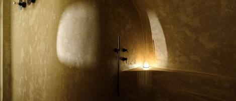 A spacious, dimly lit room with a large, curved bathtub and a small window.