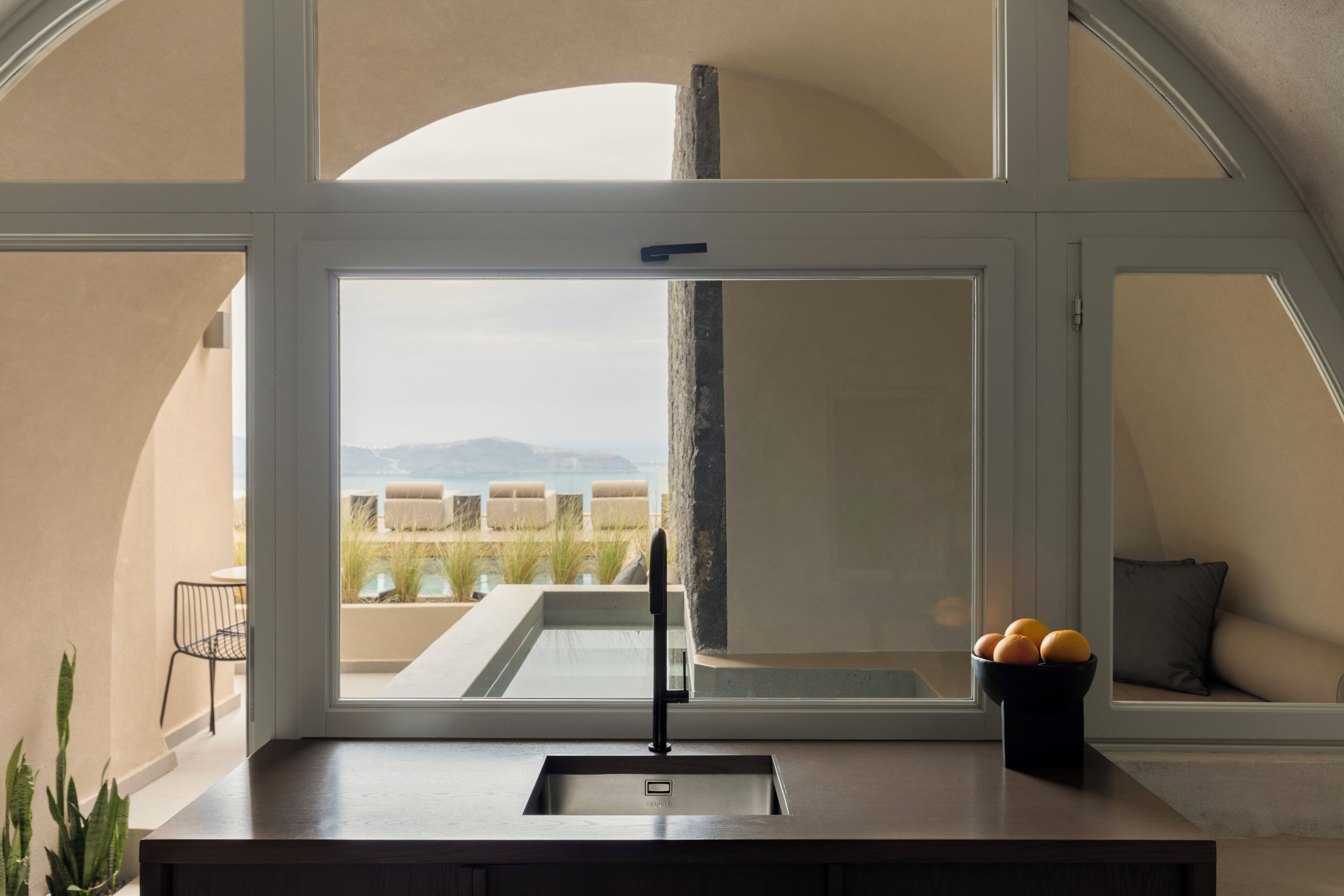 A kitchen with a window, a sink, and a bowl of fruit on the counter.