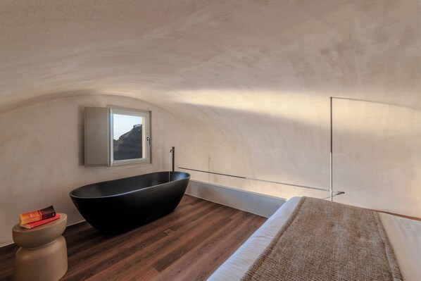 Un baño moderno con una bañera independiente, un ventanal con vistas a la montaña y suelo de madera.