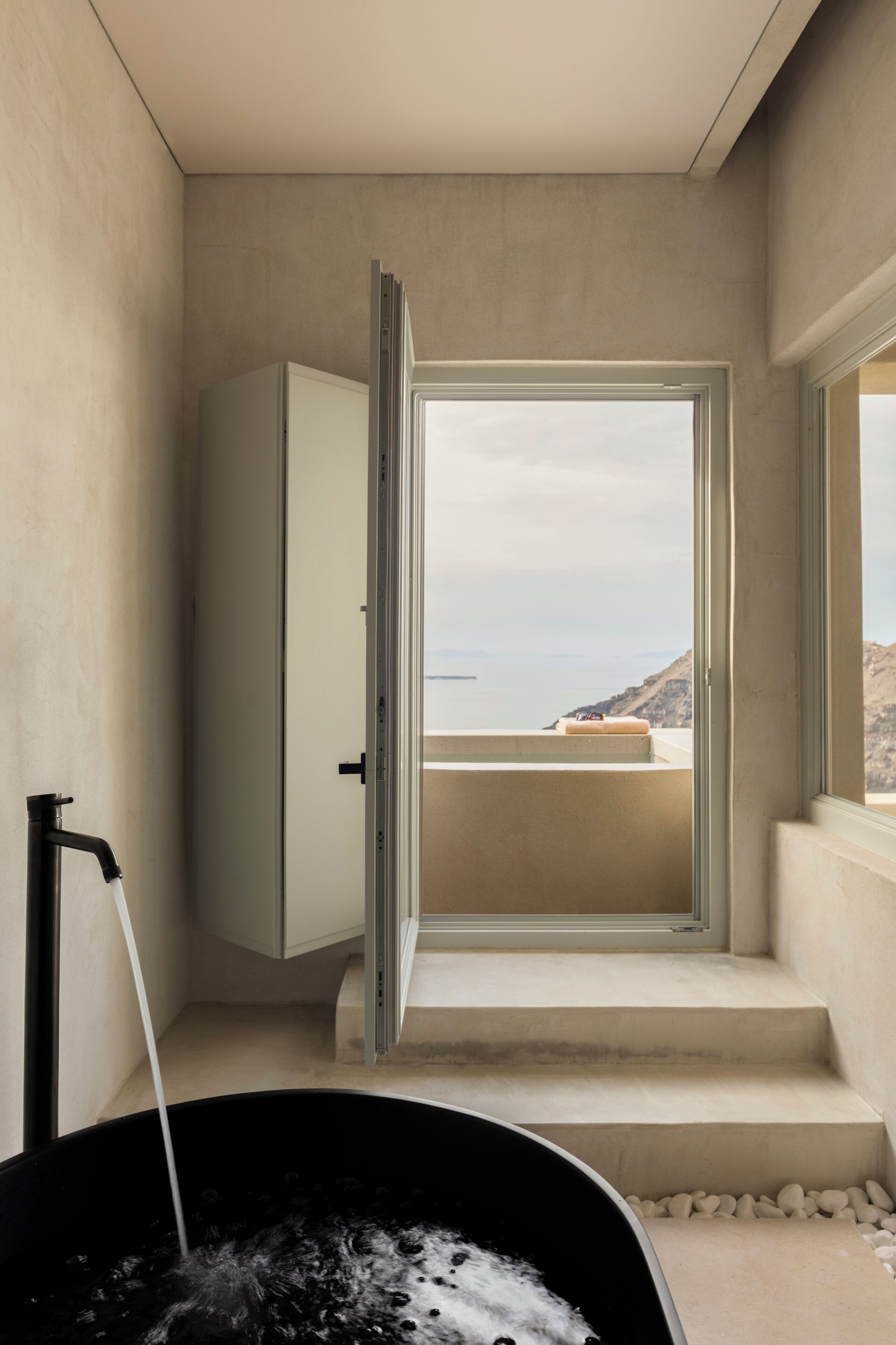 A bathroom with a bathtub, a shower, and a view of the sea.