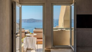 Una habitación moderna con puerta de cristal que da a un balcón con vistas al mar y las montañas.