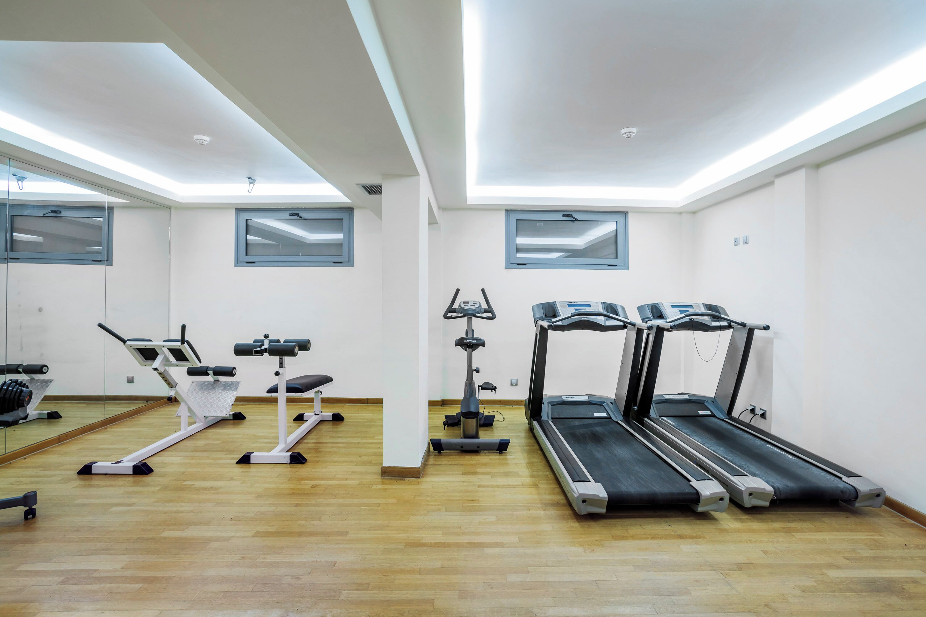Une salle de sport équipée de matériel d’exercice, notamment des tapis de course et un vélo d’appartement, et dotée d’un grand miroir mural.