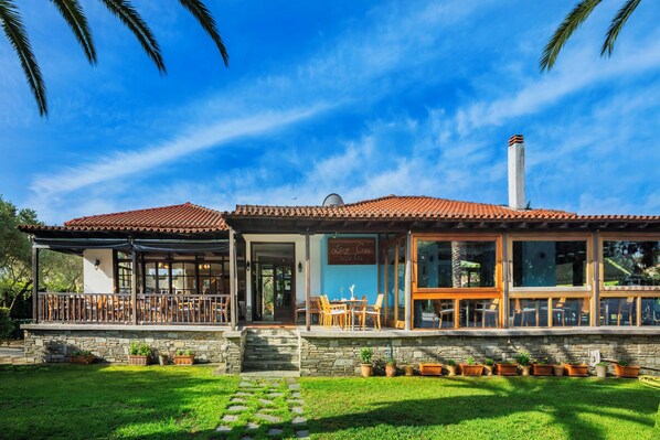 A two-story house with a patio, stone steps, and potted plants. - Hanioti Village Resort (Kassandra)