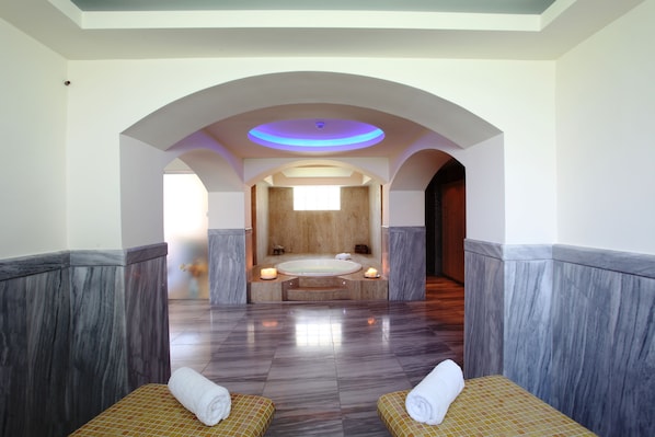 A spa room with a large bathtub, two massage chairs, and a ceiling with a circular light fixture. - Hanioti Village Resort (Kassandra)