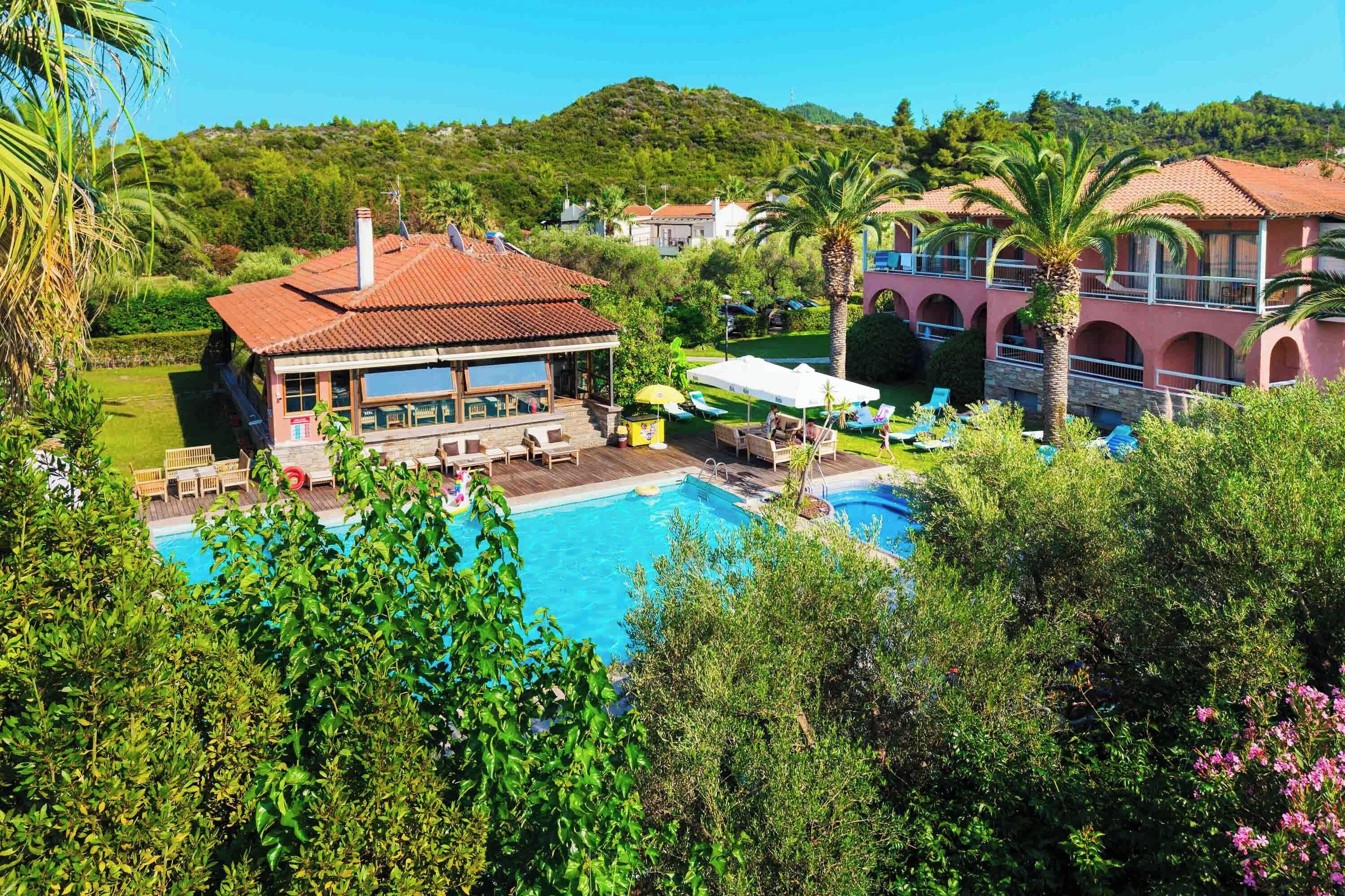A resort with a swimming pool, outdoor seating, and a view of the surrounding hills.