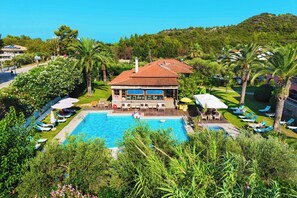 Un resort con piscina, sillones de descanso y un patio cubierto.
