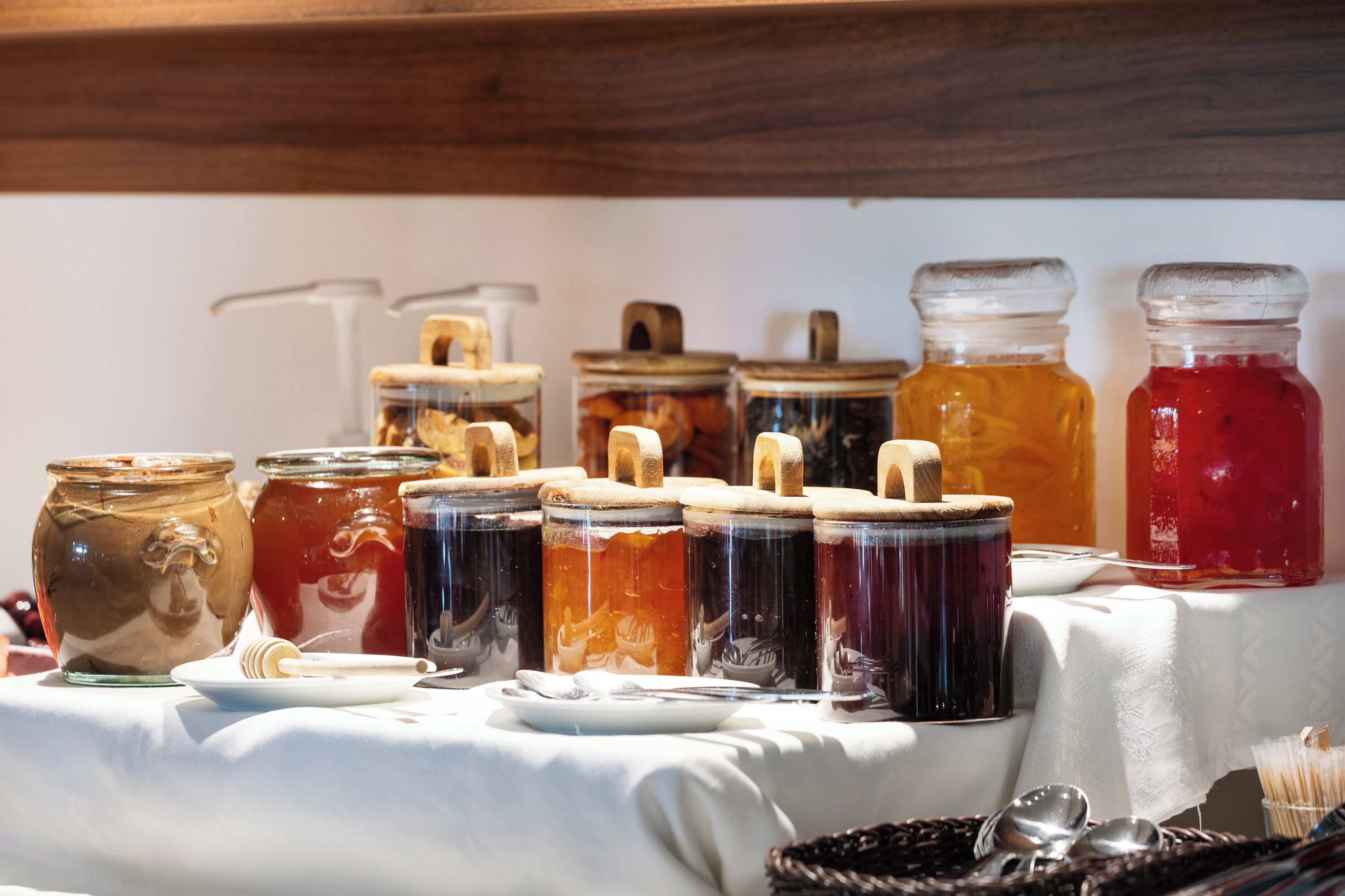 A table with various jars containing different colored liquids, some with wooden lids, and a few with metal lids.