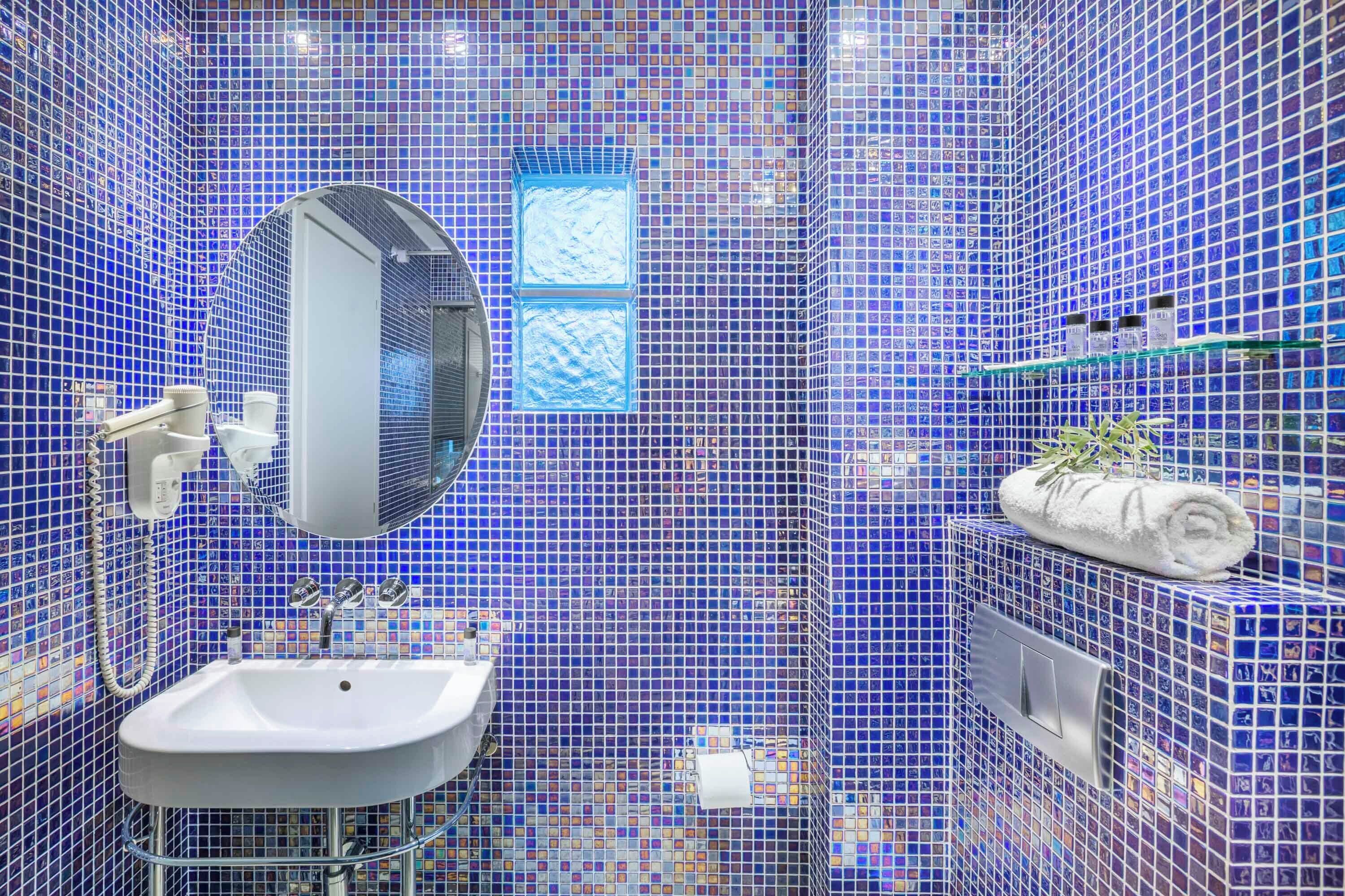 A bathroom with a sink, mirror, and tiled walls.