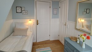 A bedroom with a bed, a dresser, a mirror, and a door. - Hotel Klostergaarden (Allinge)