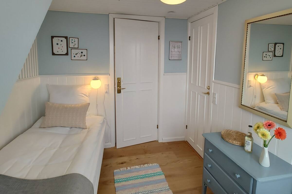 A bedroom with a bed, a dresser, a mirror, and a door.