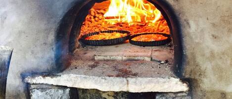 Un four à briques contenant deux plaques à pizza, avec des flammes visibles et une base en béton.
