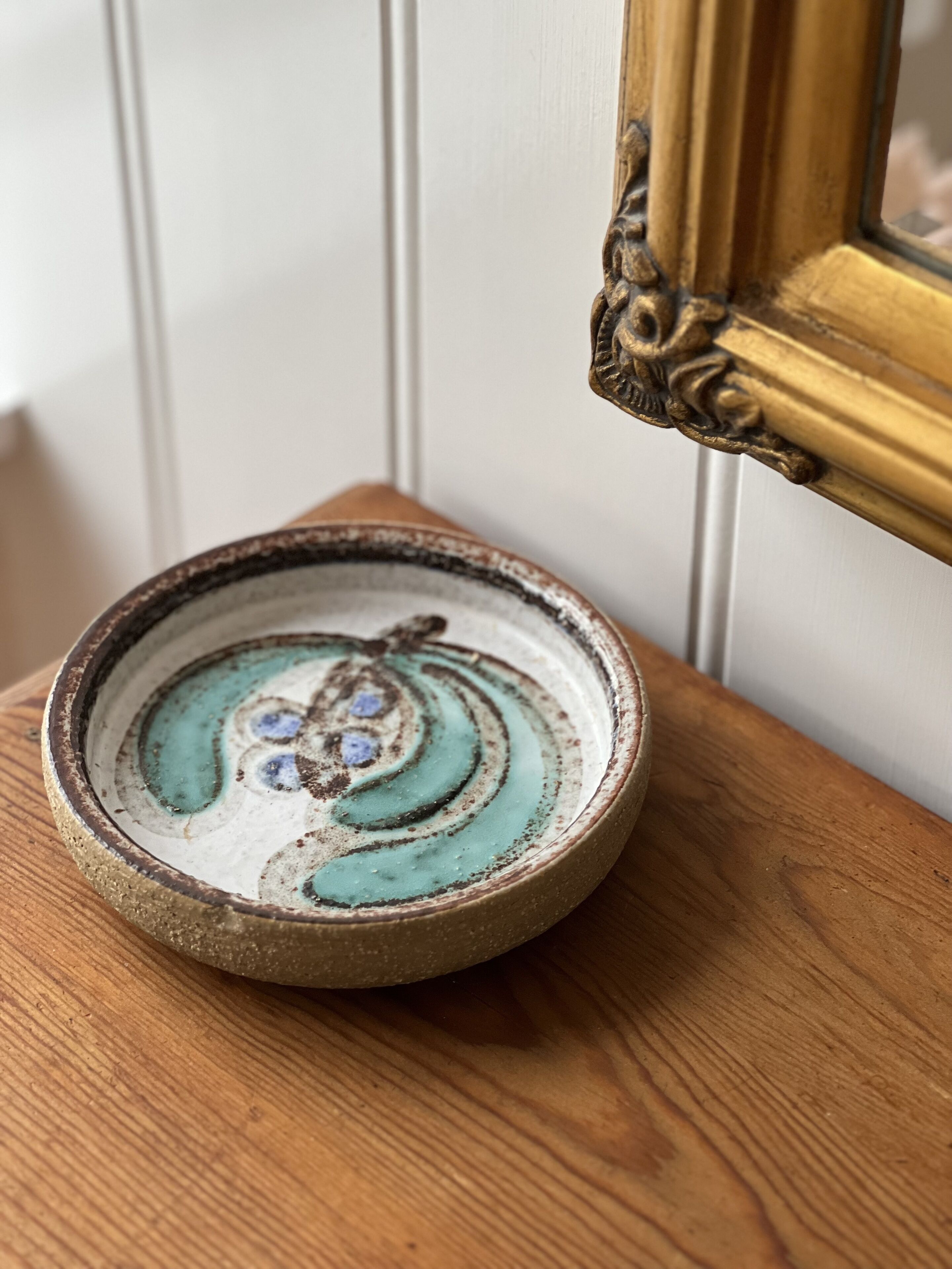 A rustic ceramic bowl with a spiral design on a wooden surface.
