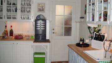 A kitchen with white cabinets, a coffee machine, a green trash bin, and a wine rack.