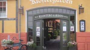 The entrance to Klostergaarden Hotel with a bicycle parked outside and flower baskets on the steps. - Hotel Klostergaarden (Allinge)