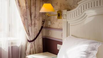 Een hotelkamer met een bed, nachtkastje, lamp en gordijnen.