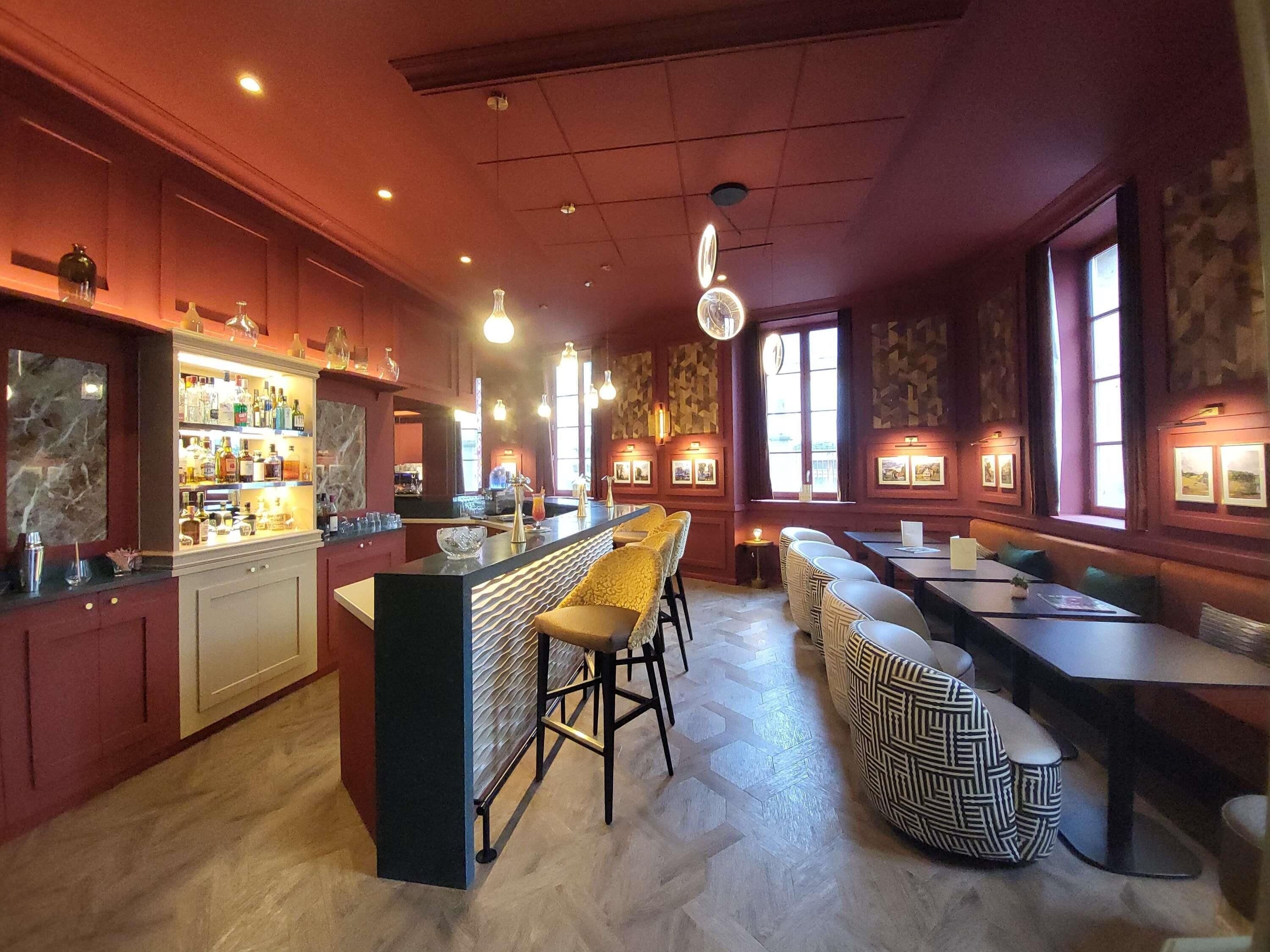 A bar area with a counter, stools, and a seating area with tables and chairs.